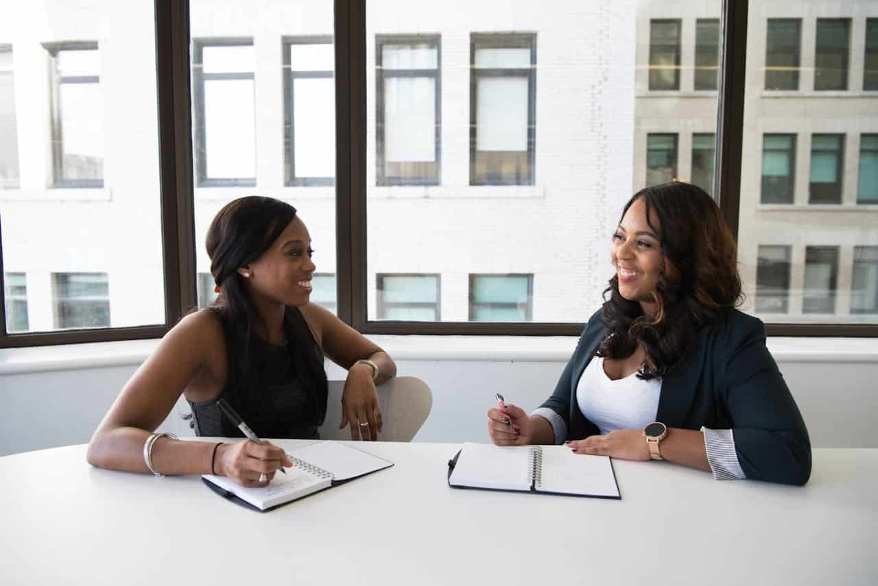 Photo by Christina Morillo: https://www.pexels.com/photo/two-woman-in-black-sits-on-chair-near-table-1181605/ -- professional women, event planner, business meeting