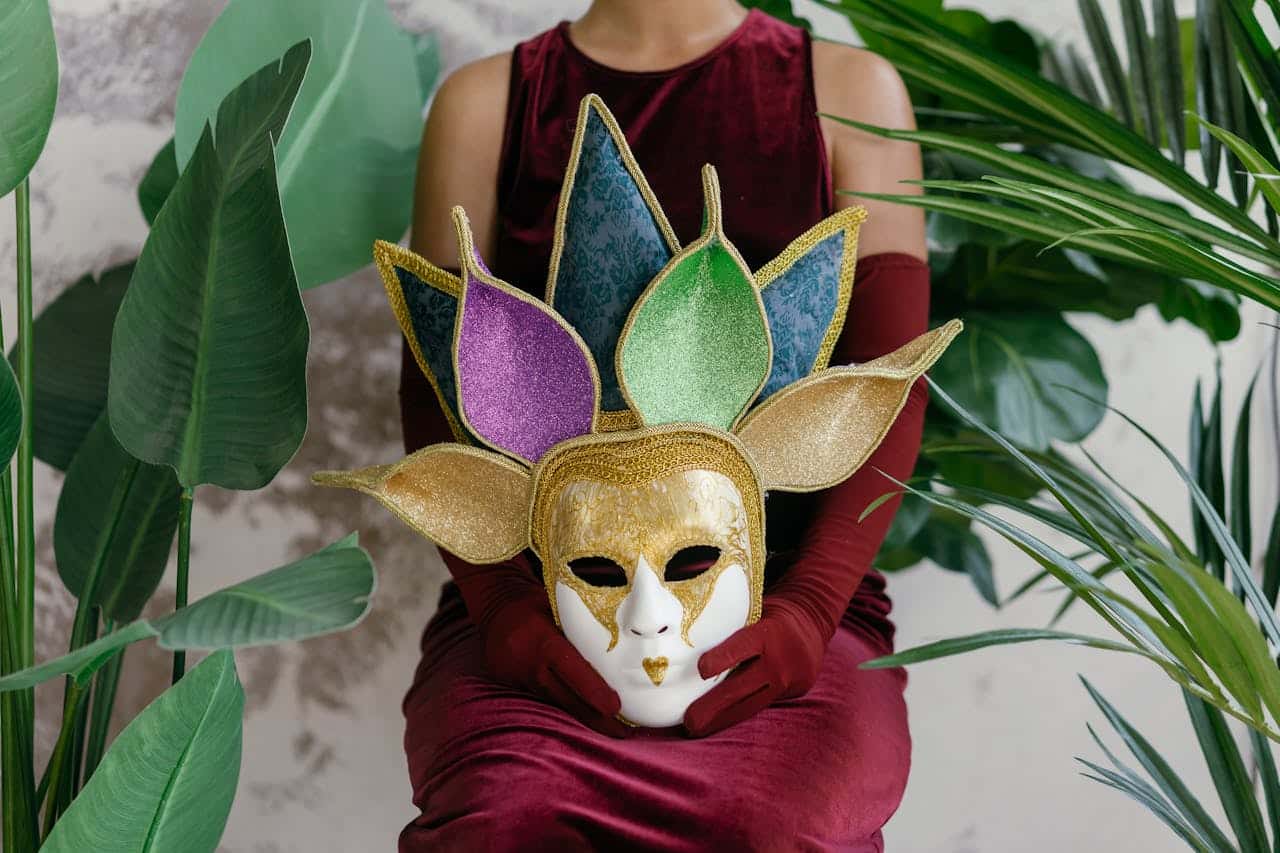 Photo by Mikhail Nilov: https://www.pexels.com/photo/woman-sitting-and-holding-a-carnival-mas-9391495/ -- imposter mask