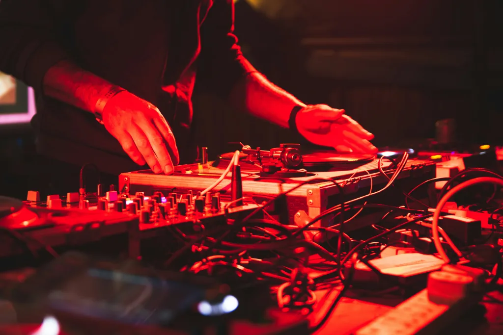 https://unsplash.com/photos/a-dj-mixing-music-in-a-dark-room-OXQIWnA7xOU Photo by Tim Macknelly on Unsplash