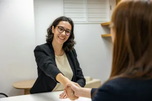 https://unsplash.com/photos/a-woman-shaking-hands-with-another-woman-sitting-at-a-table-IESB4iFVuzA Photo by Resume Genius on Unsplash