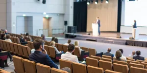 Event professionals at a B2B marketing summit listen to a speaker on stage.