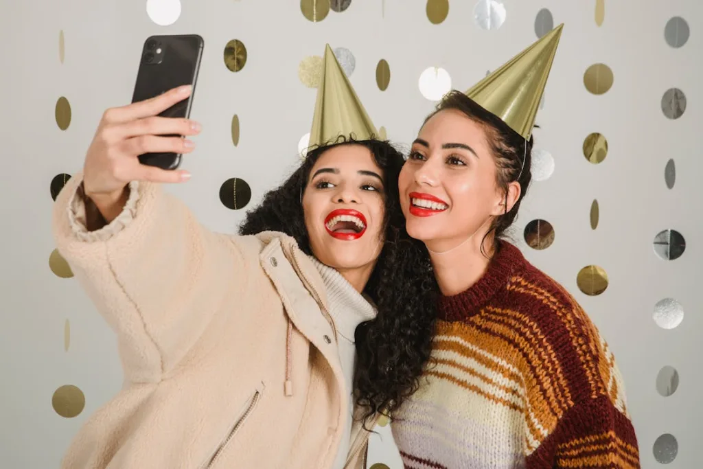Photo by Julia Larson : https://www.pexels.com/photo/cheerful-women-in-party-hats-taking-selfie-on-smartphone-6113202/