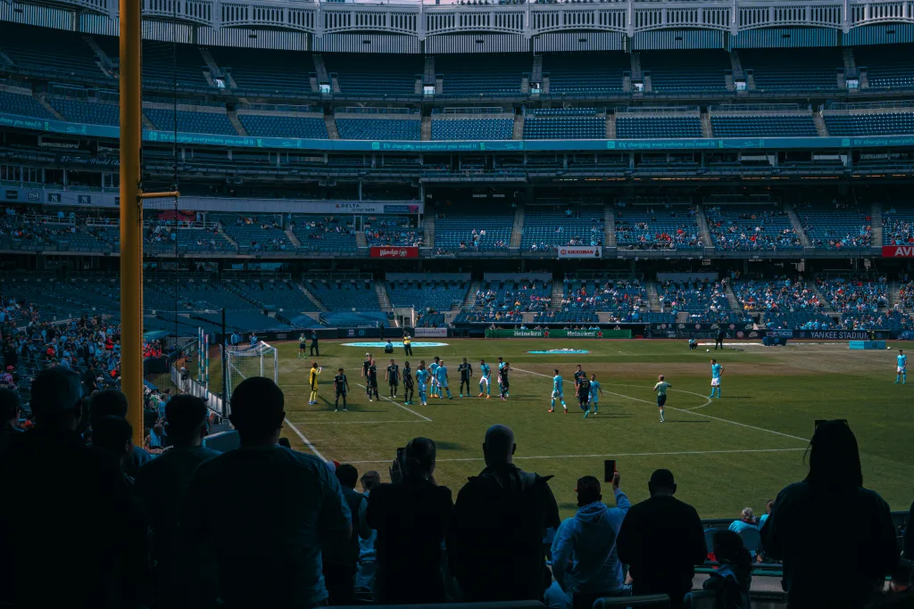 https://unsplash.com/photos/a-group-of-people-standing-on-top-of-a-soccer-field--_kPhmgL6KY Photo by Benjamin Cutting on Unsplash