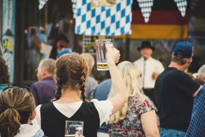 https://www.pexels.com/photo/woman-standing-in-a-crowd-holding-up-beer-glass-1467807/